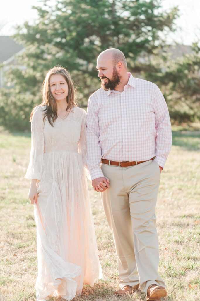 Engaged couple smiling at camera with green trees in background