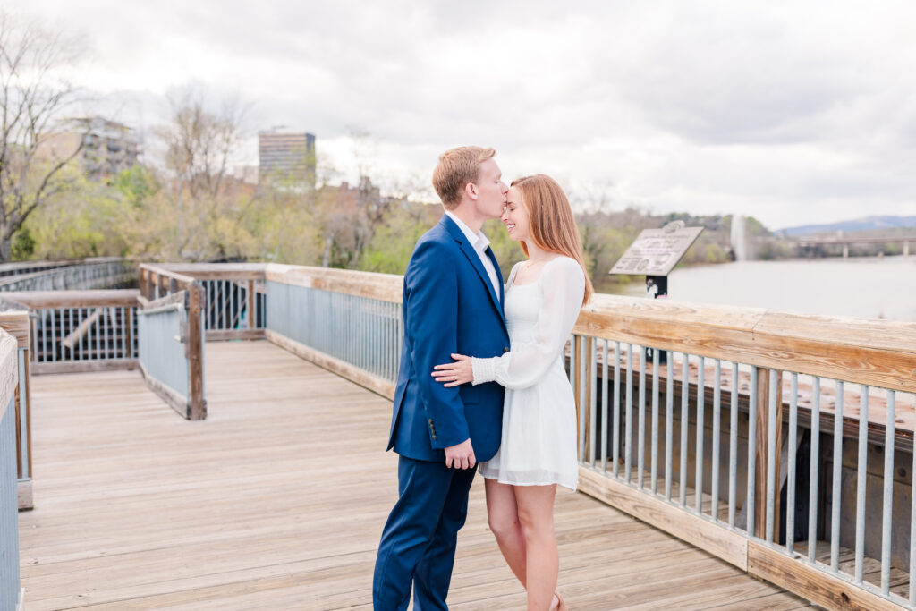 groom to be kissing his bride to be on the forehead at their Virginia Engagement Session on Percival's Islands Bridge in Virginia