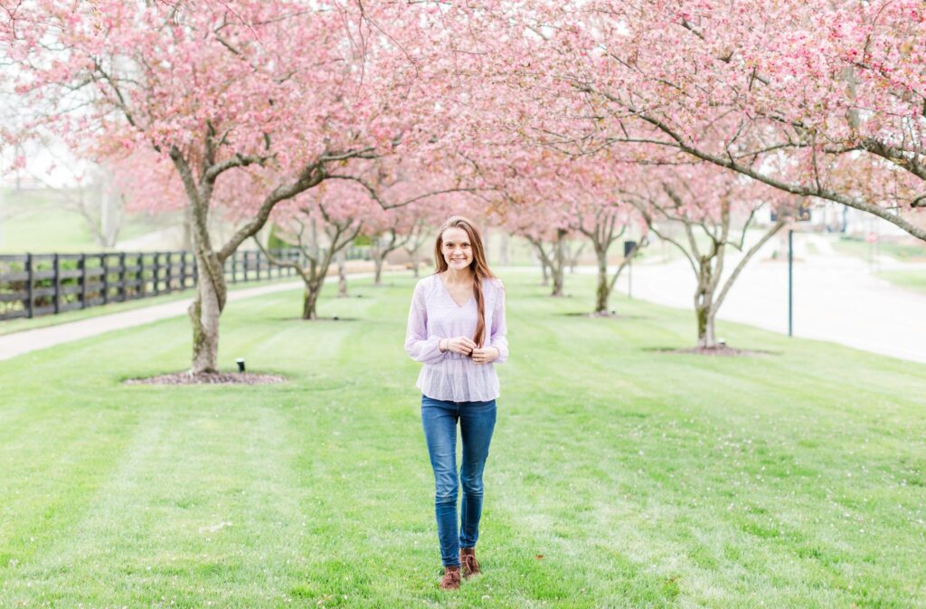 Jennifer Cooke, wedding photographer, is walking around and smiling in an Eastern redbud patch excited to tell you about HoneyBook's online contract signing software!