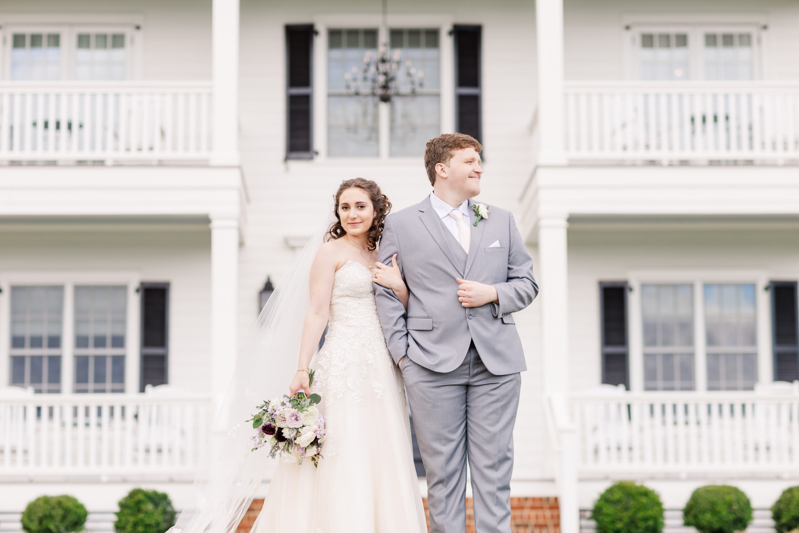 bride and groom posing in front of their manor house wedding venue on their wedding day