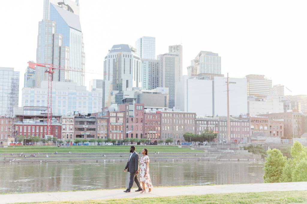 Engaged couple walking along the Nashville Riverfront during their Cumberland Park Engagement with Jennifer Cooke Photography. 