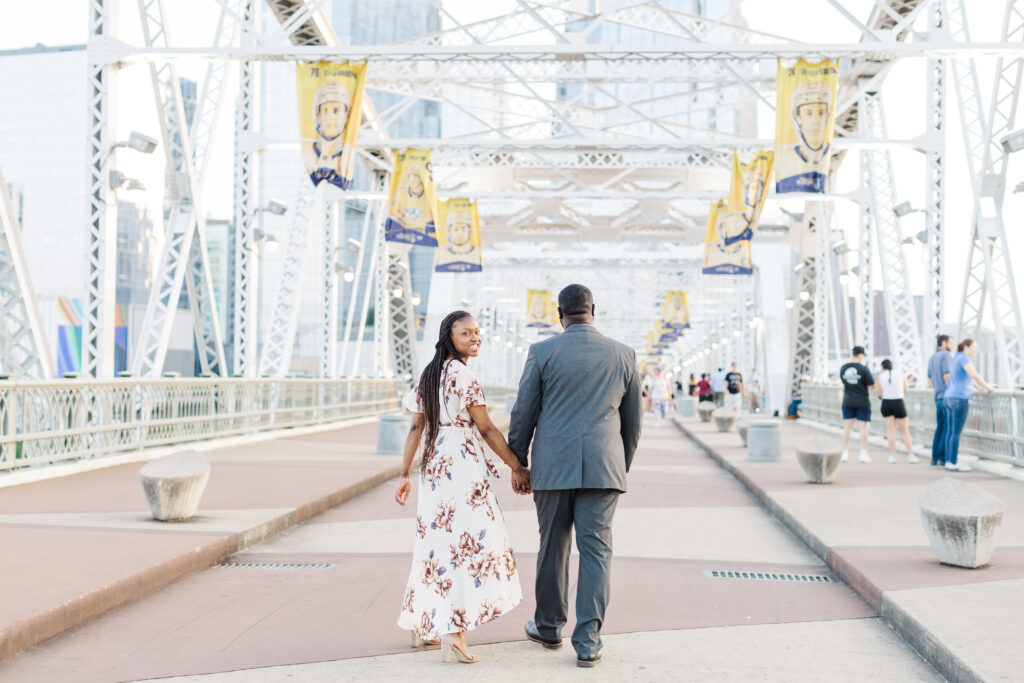 Couple walking across the Nashville Pedestrian Bridge during their Cumberland Park Engagement Session. 