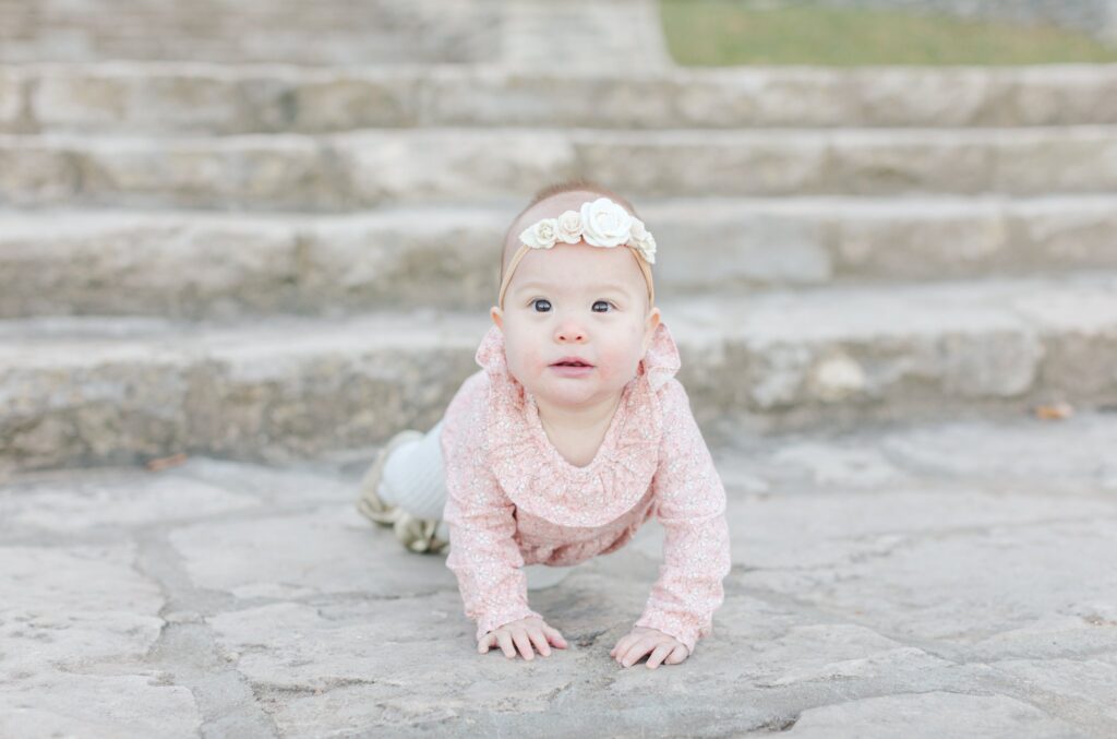 Toddler wearing pink clothes crawling at Percy Warner Steps