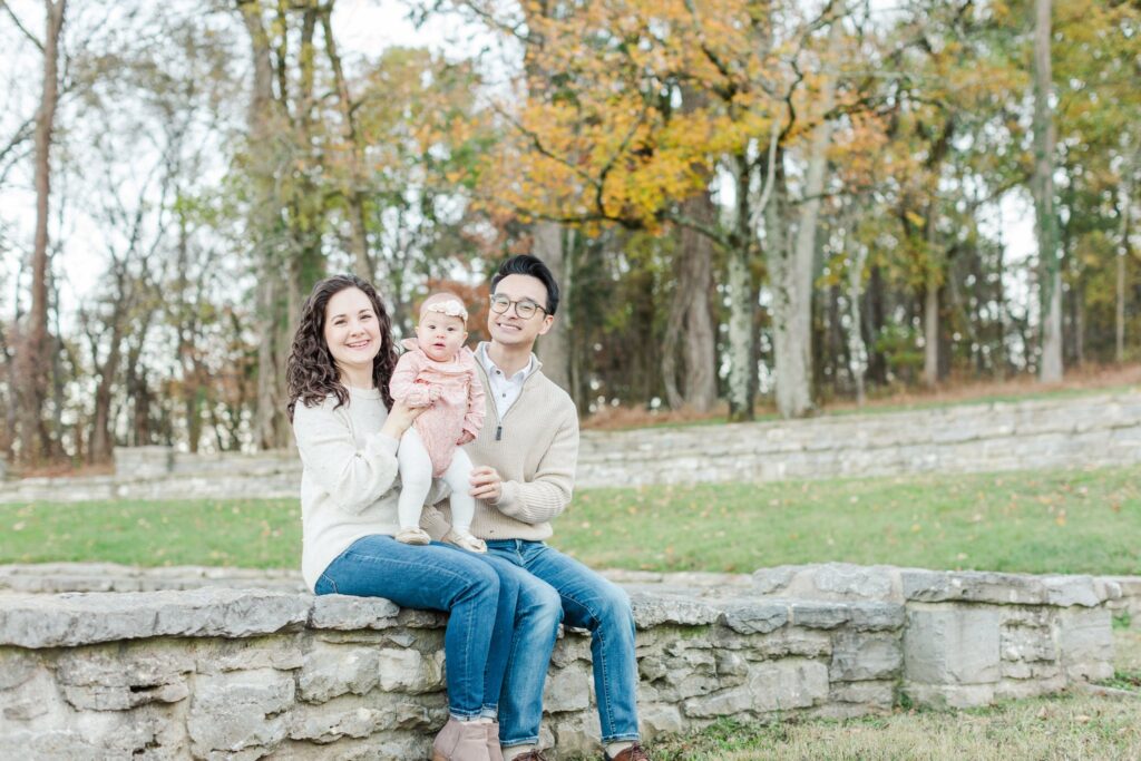 family of three smiling while sitting on stone wall at Percy Warner Steps