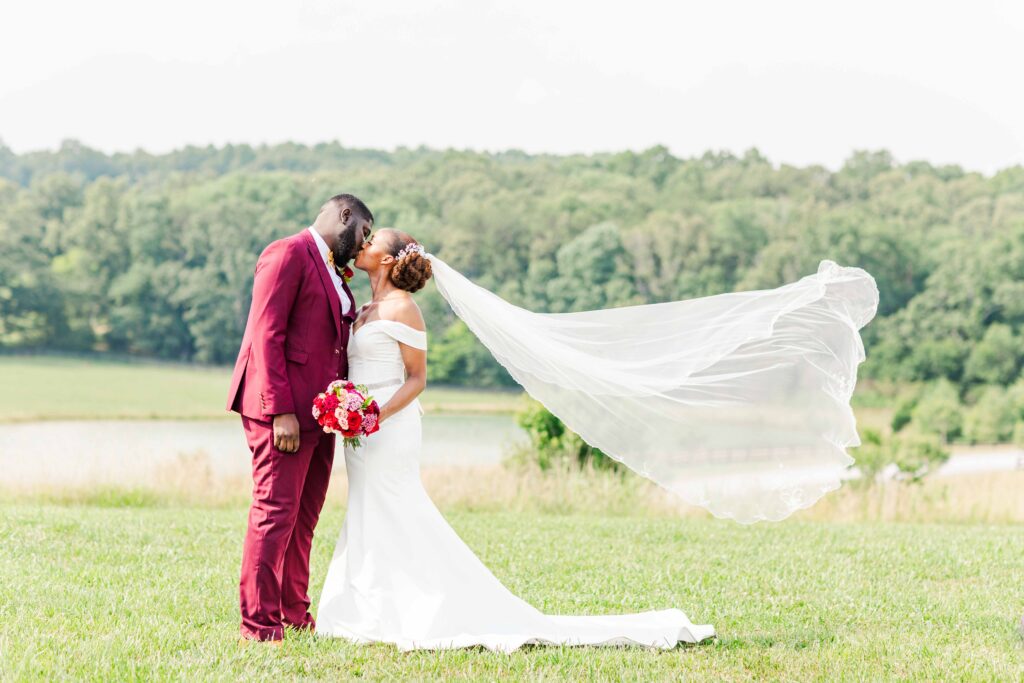 Invest in Your Wedding Photographer, couple kissing while veil is flying in the wind