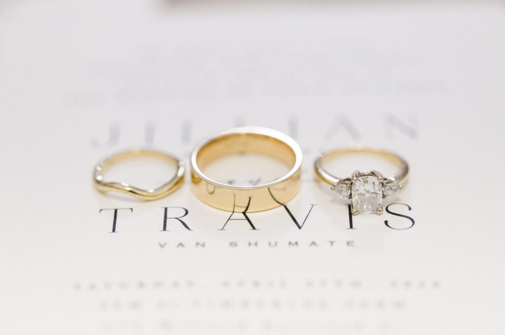 three beautiful rings together on top of a white wedding invitation, Invest in Your Wedding Photographer