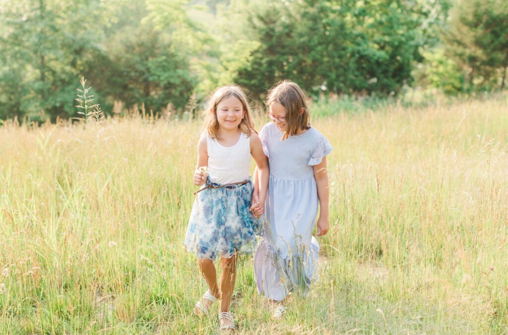 Two girls running together in a bright, summer field