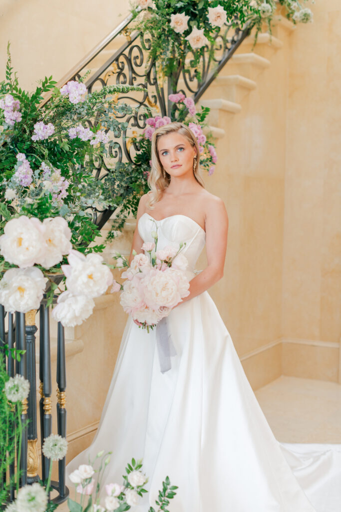 Bride posing by a luxurious floral staircase