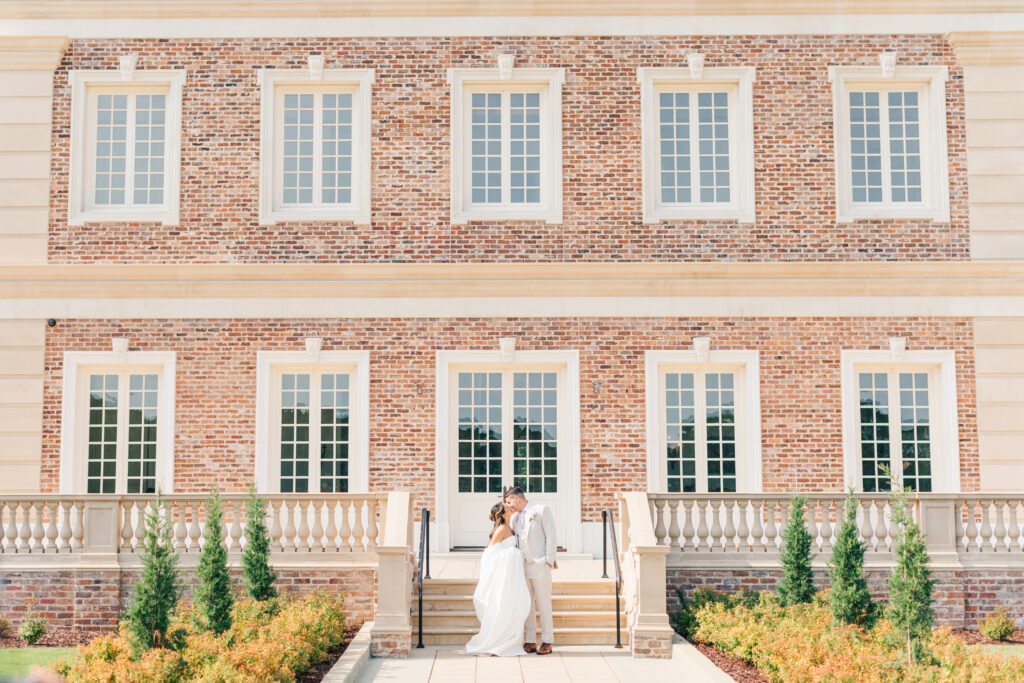 Married couple kissing in front of Oxbow Estate