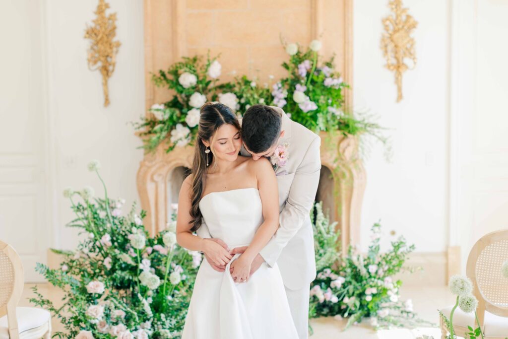 groom kissing bride's shoulder surrounded by beautiful green and lavender florals, Invest in Your Wedding Photographer