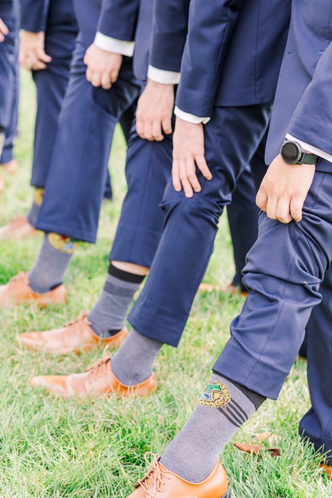 Groomsmen showing their fun Harry Potter socks for a photo at the White Dove Barn