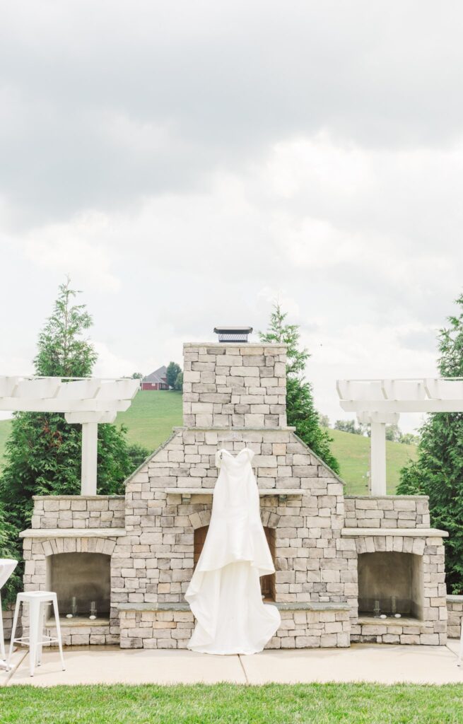 White, elegant dress hanging on a stone fireplace at the White Dove Barn in Beechgrove, TN