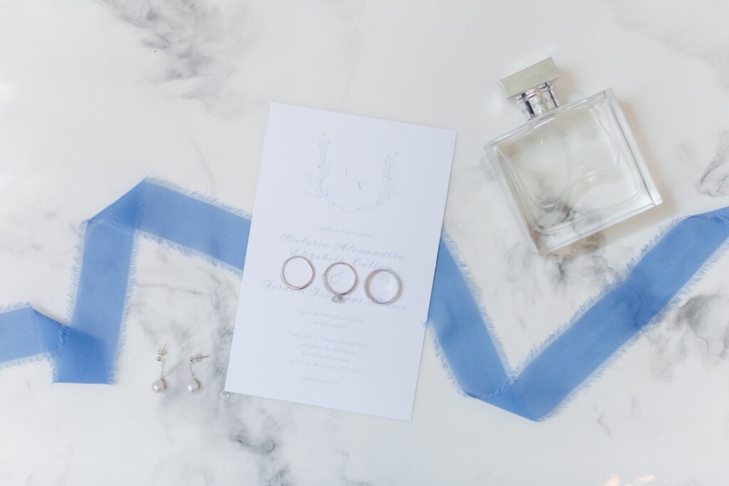 Invitation, perfume, rings, and earrings at a wedding at the White Dove Barn