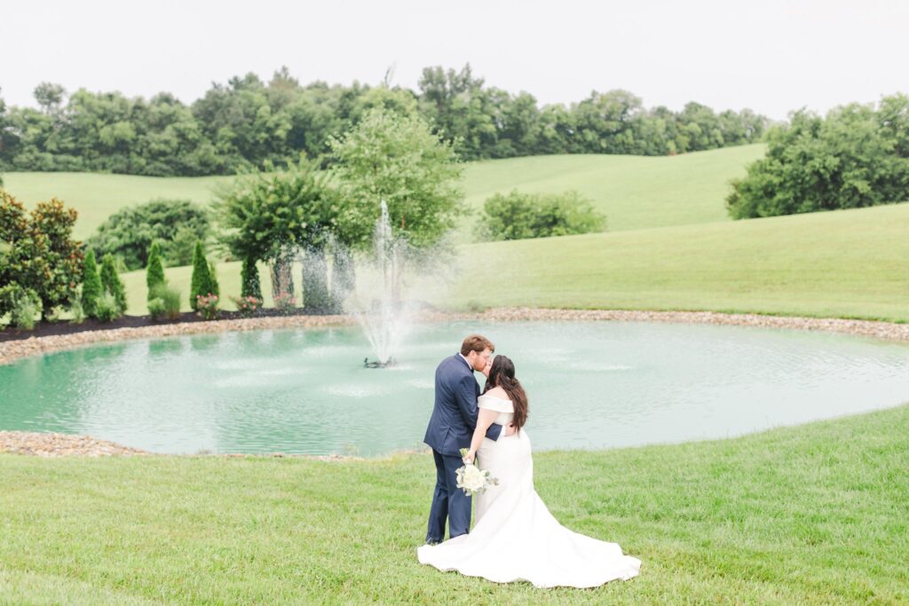 Married couple kissing in front of the pond at the White Dove Barn