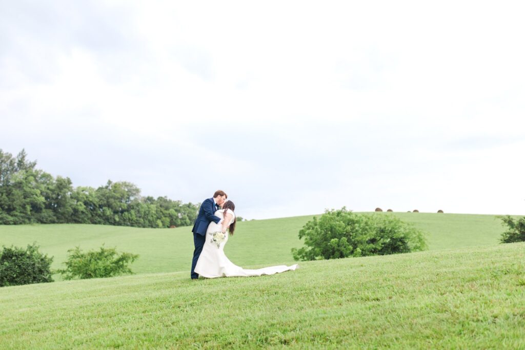 Bride and groom kissing on the rolling hills at White Dove Barn