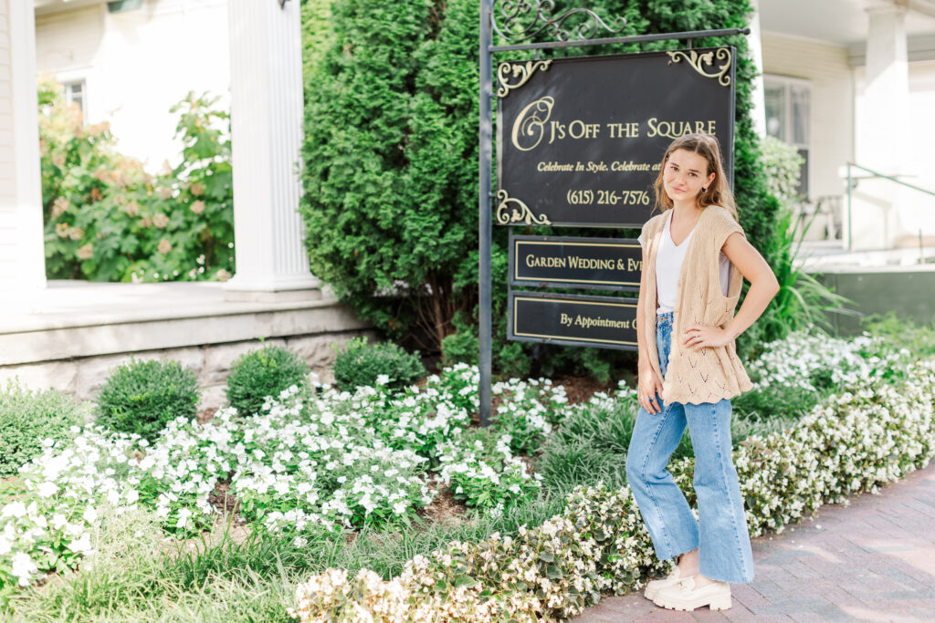 Emeline, CJ's Off the Square Venue Coordinator, posing by sign