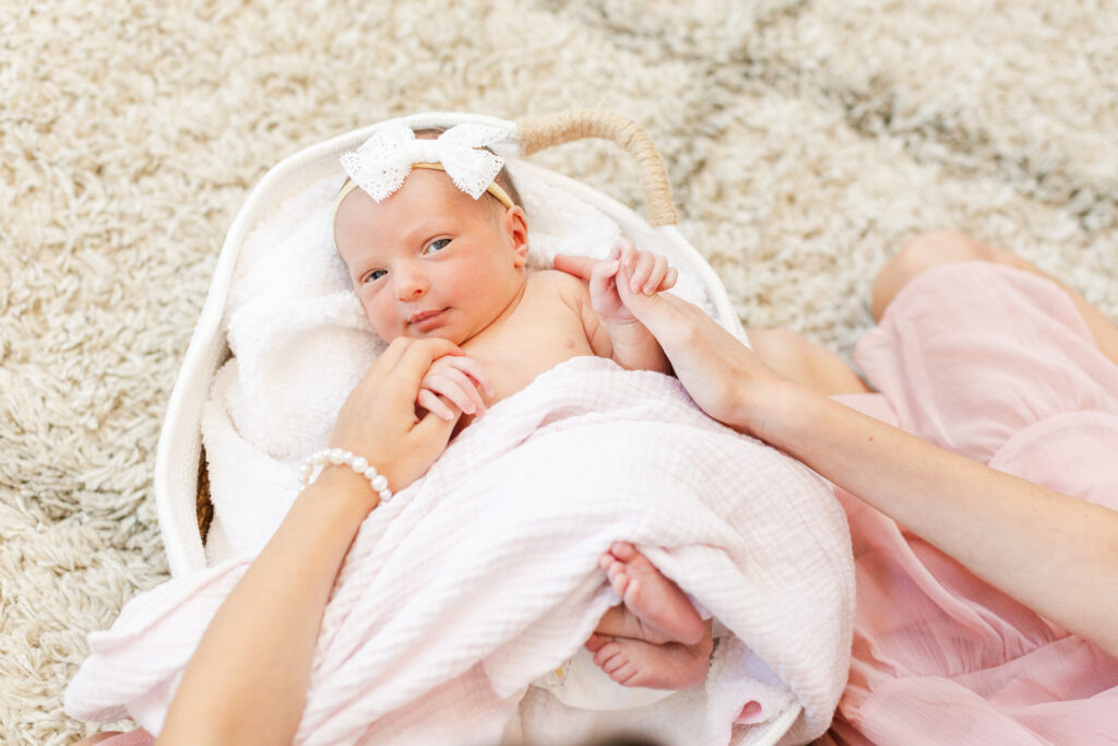 adorable newborn in a white basket with a pink swaddle